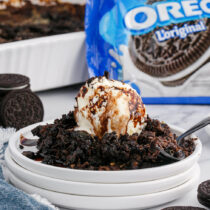 Oreo Dump Cake on a white plate with a scoop of ice cream.