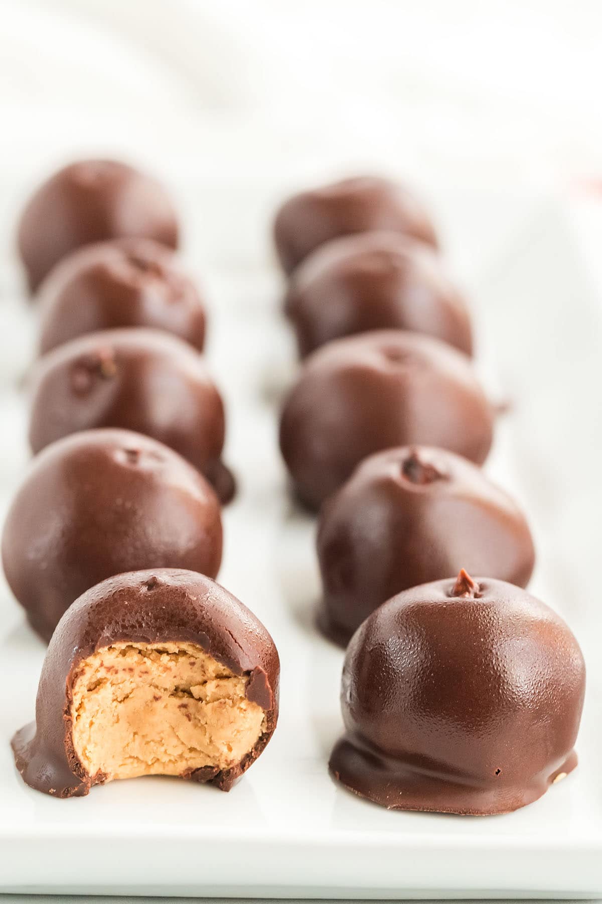 a couple of peanut butter balls lined up on a white plate.