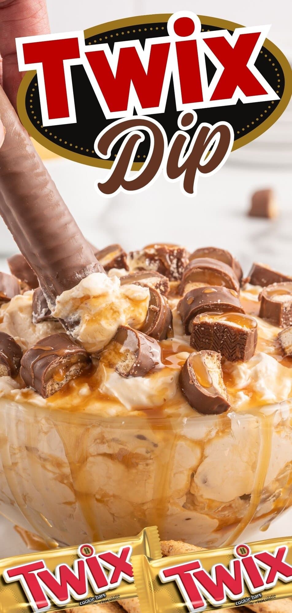 Close up of Twix dip inside a clear glass bowl, combination of cream cheese, whipped topping, caramel and pieces of Twix on top.