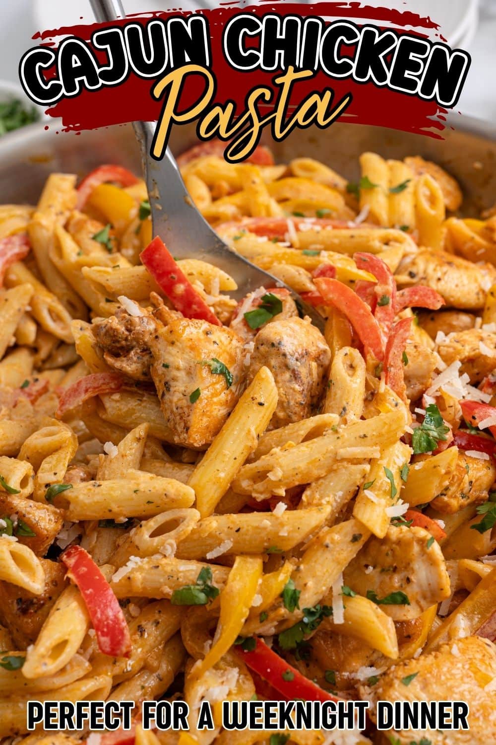 Close-up of a spoon lifting Cajun chicken pasta with bell peppers and parmesan from a skillet.