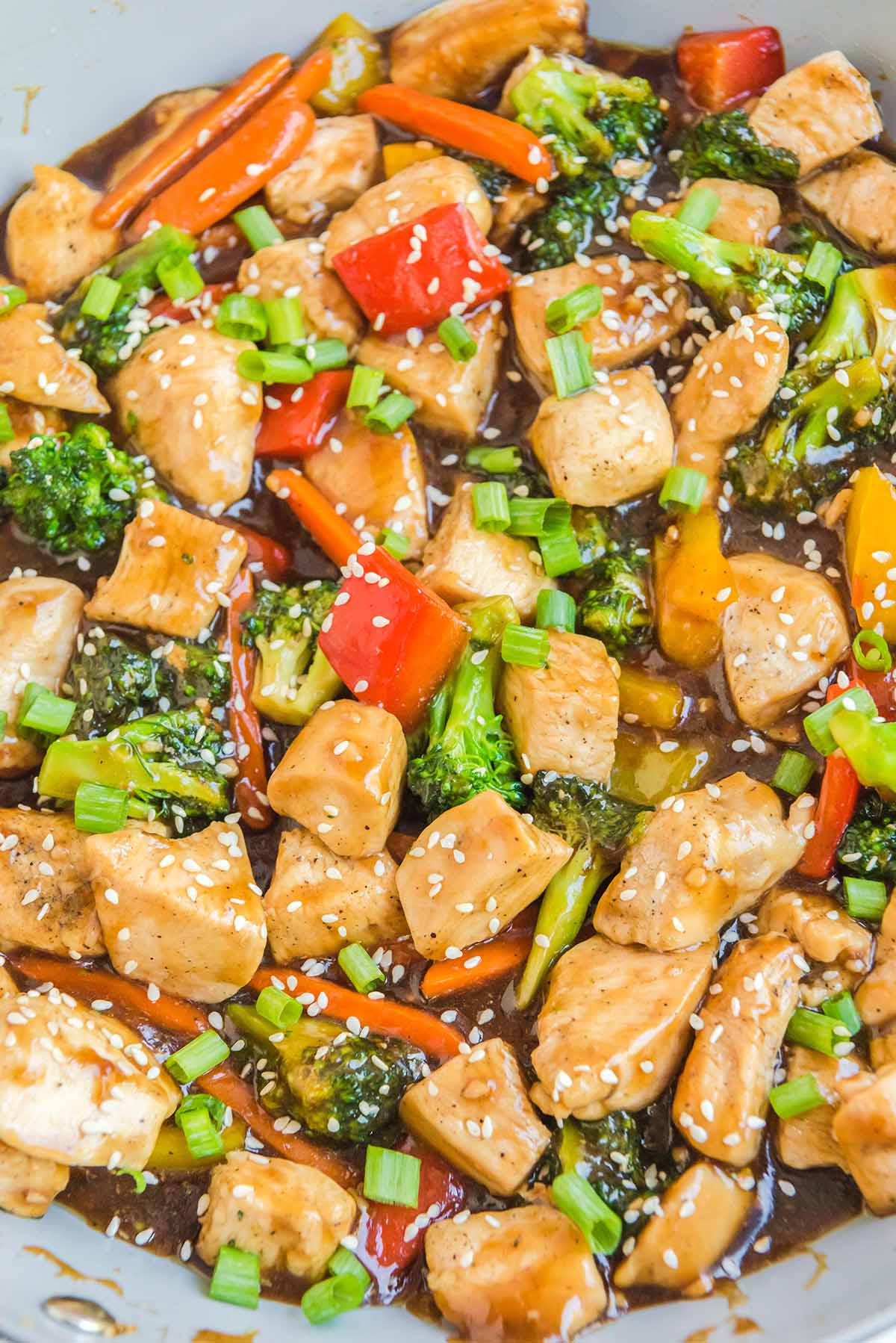 chicken stir fry in a pan sprinkled with sesame seeds.