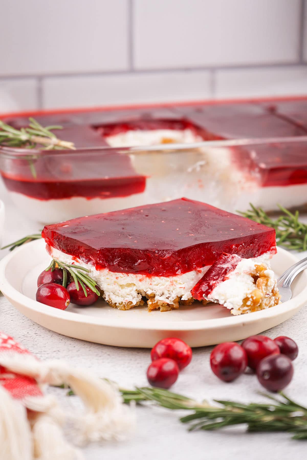 Cranberry Pretzel Salad on a plate and a couple fresh cranberries on the table.