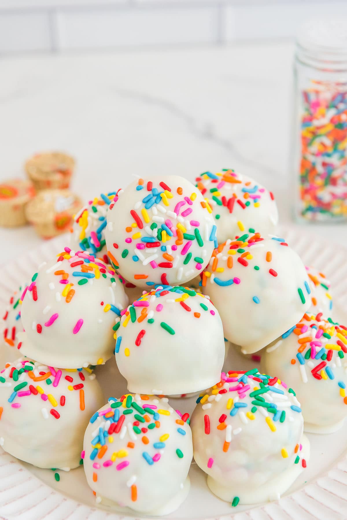 Surprise Inside Cheesecake Bites with sprinkles on a white plate.