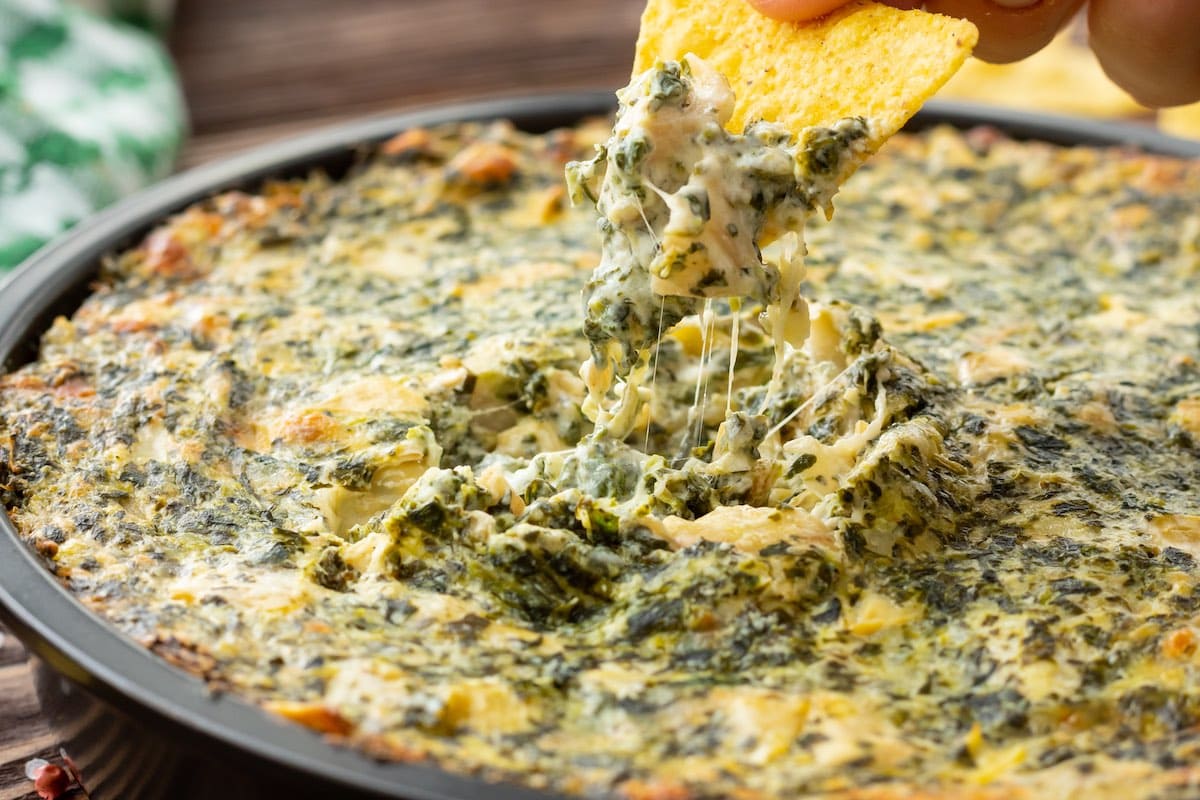 dipping cracker into the Spinach Artichoke Dip