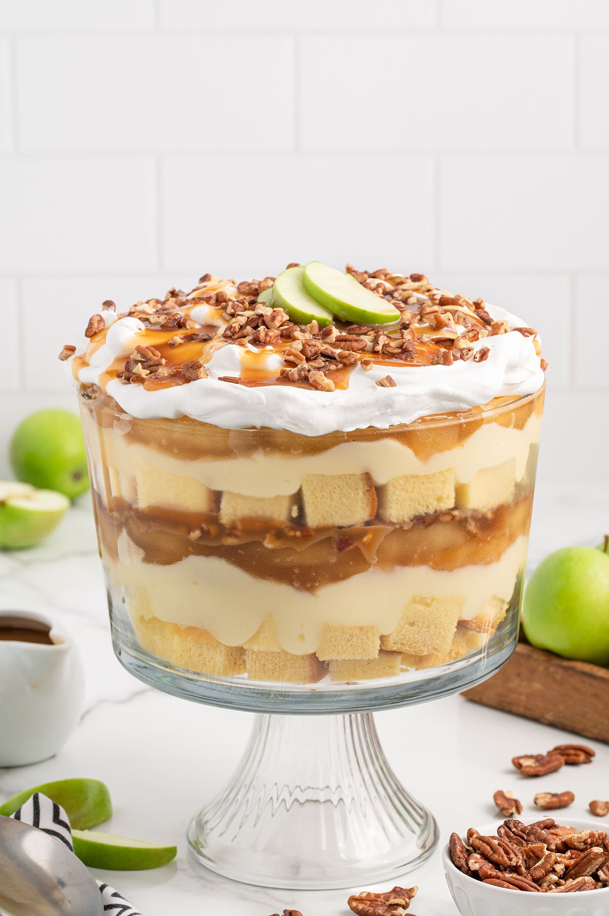 Caramel Apple Trifle in a trifle bowl topped with chopped pecans and apple slices.