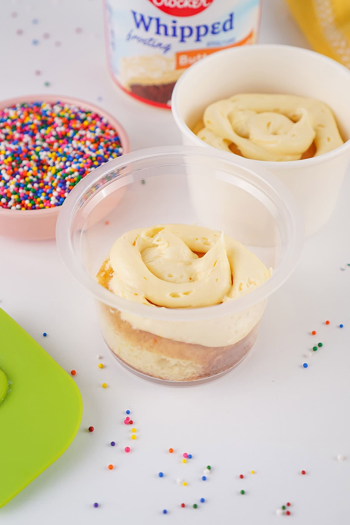 Vanilla cake layer topped with a swirl of creamy frosting in a dessert cup.
