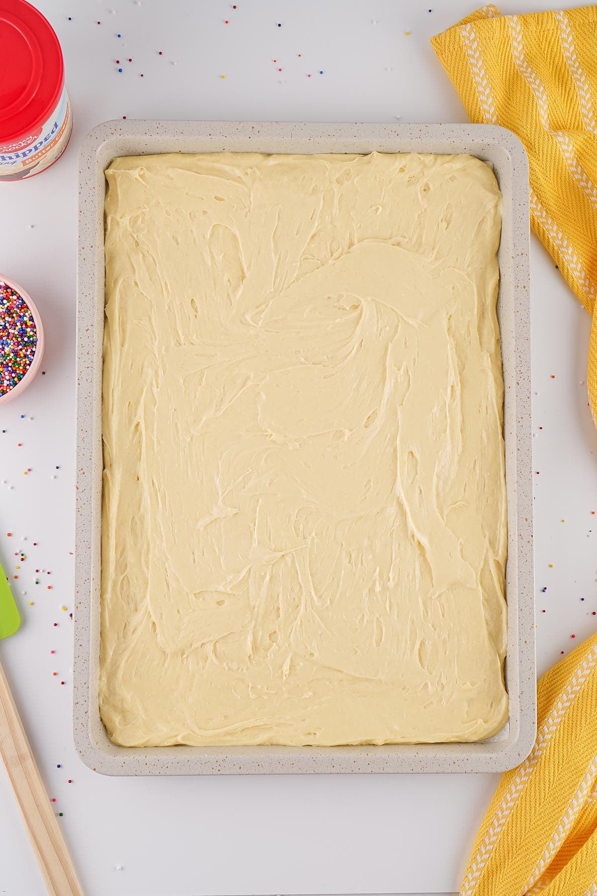 Cake topped with a smooth layer of vanilla frosting.