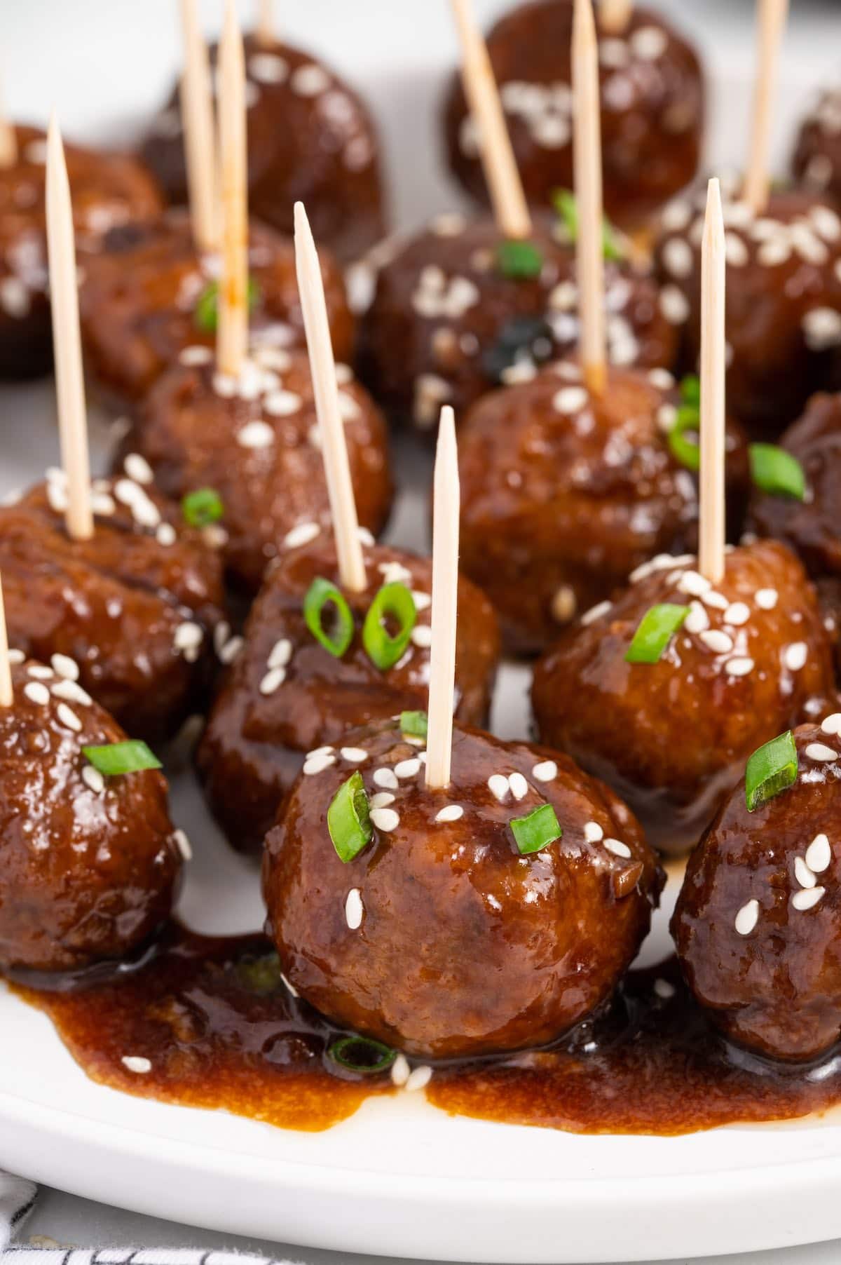 Teriyaki Meatballs topped with scallions and sesame seeds served using toothpick.