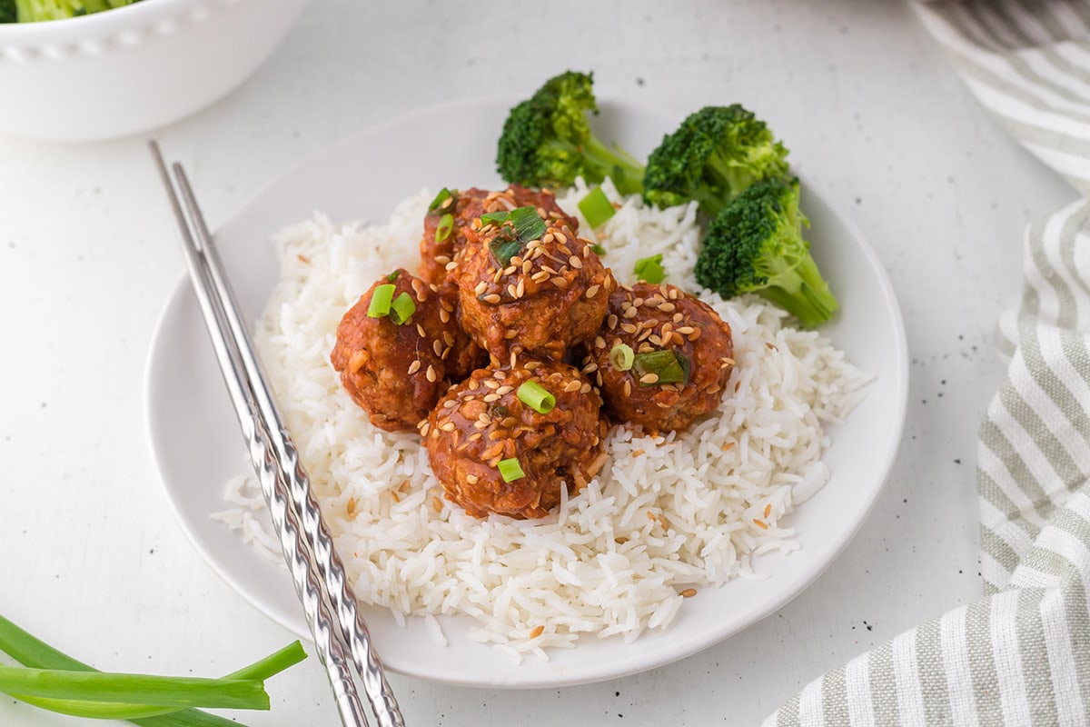 Asian Meatballs in a white plate served over rice.