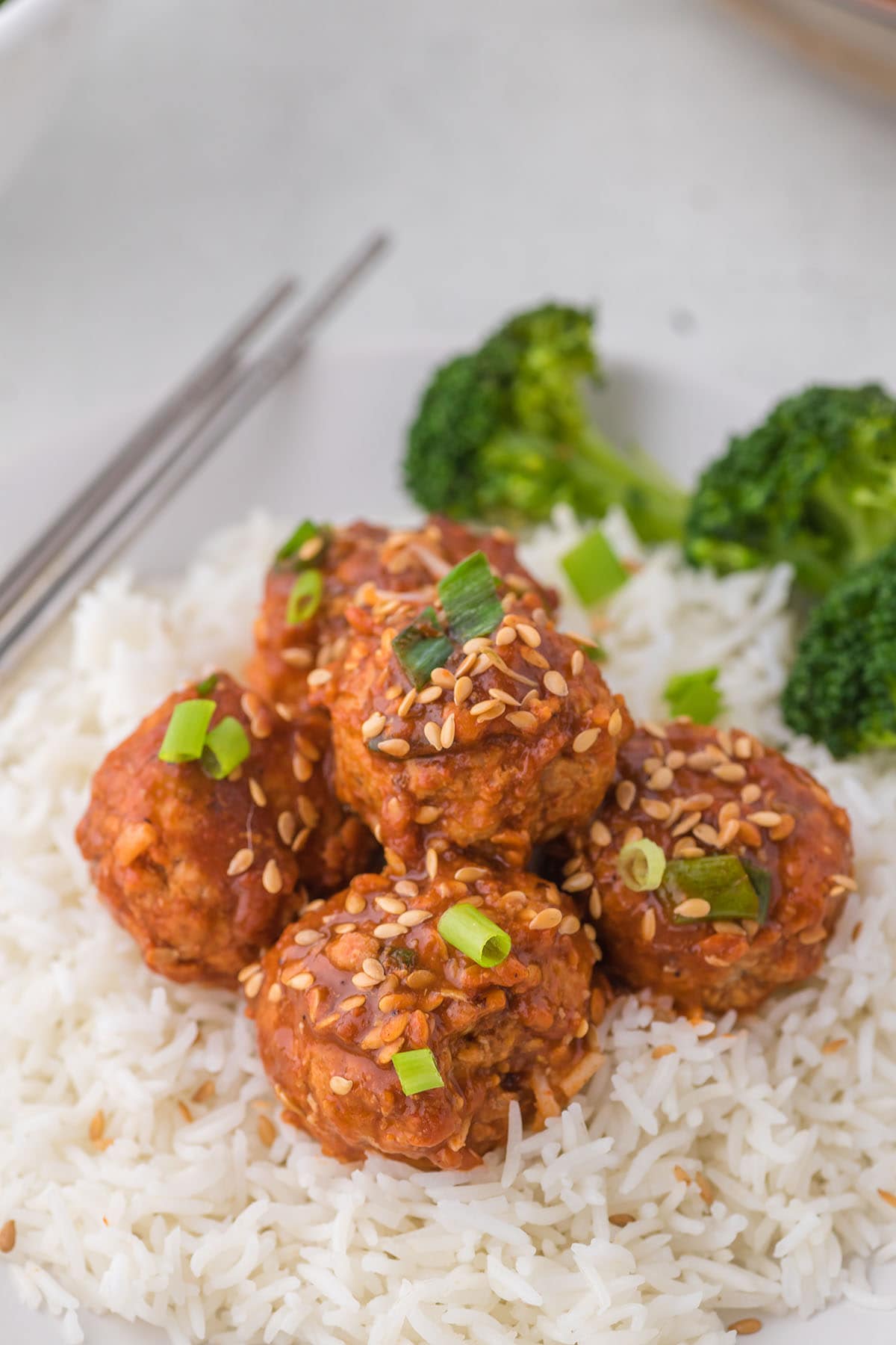 Asian Meatballs over rice with broccoli at the side.