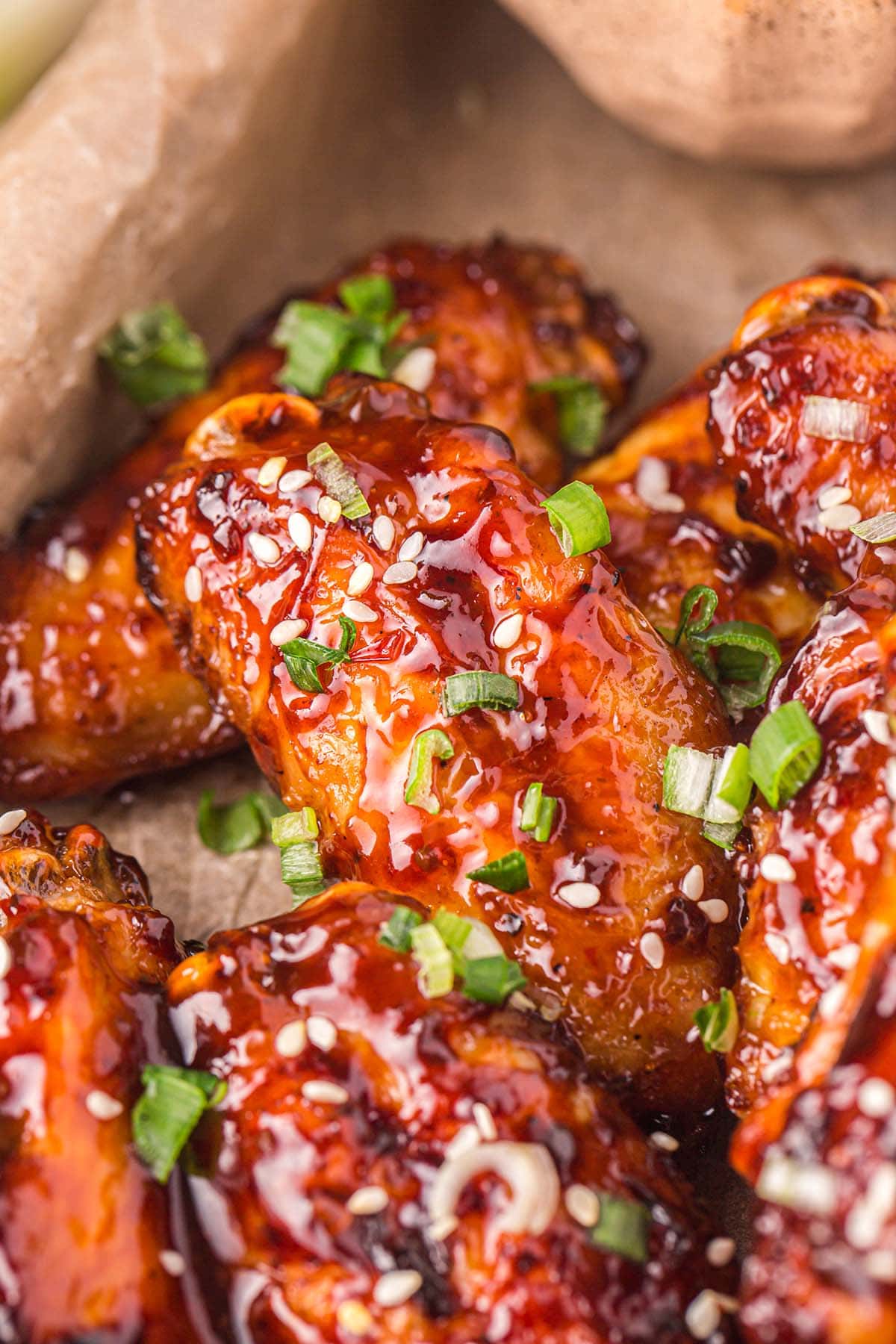 Air Fryer Asian Sticky Wings coated with sauce sprinkled with spring onions.