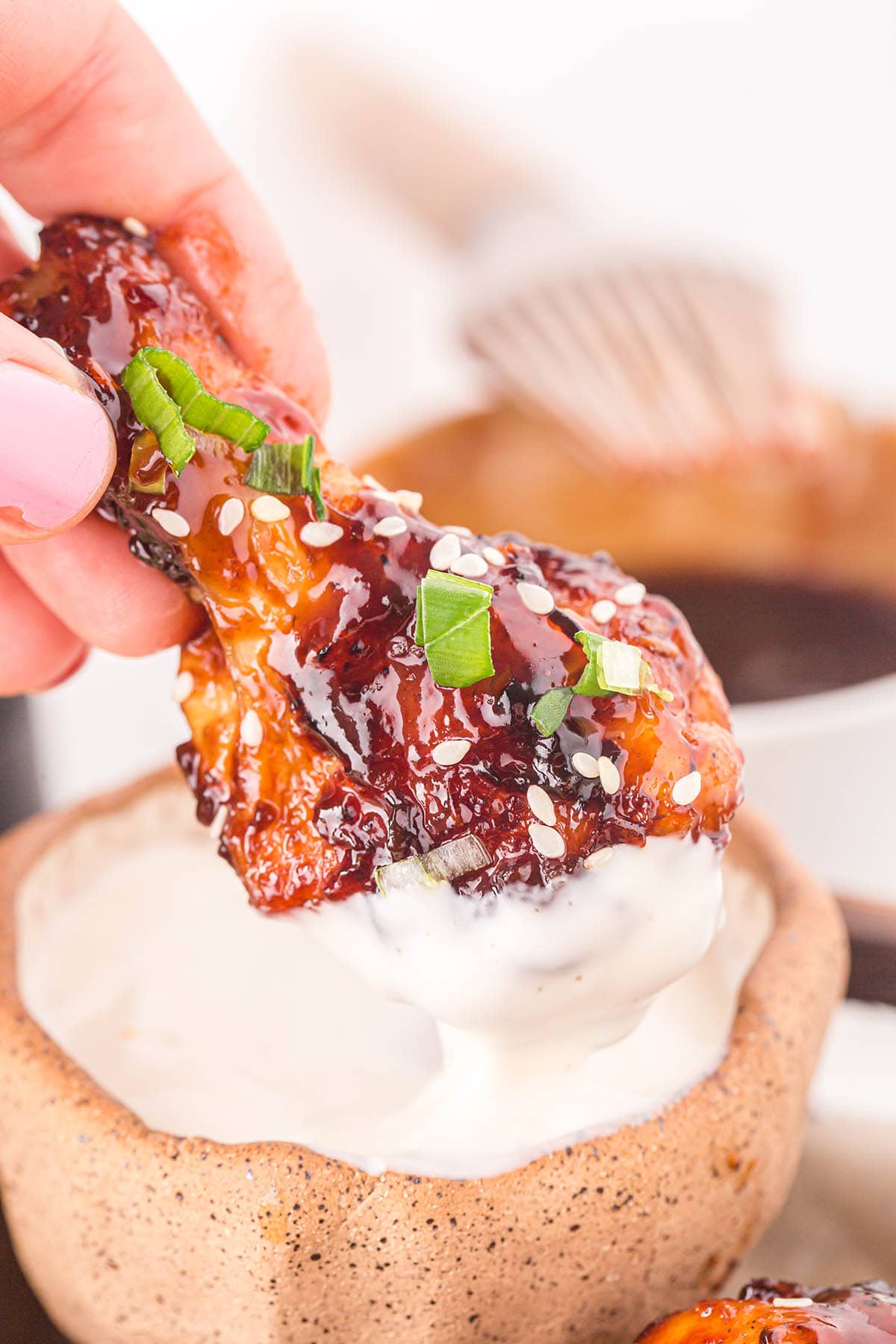 Air Fryer Asian Sticky Wings dipped in sauce.