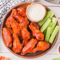 Instant Pot Buffalo Wings served with celery in a wooden plate.