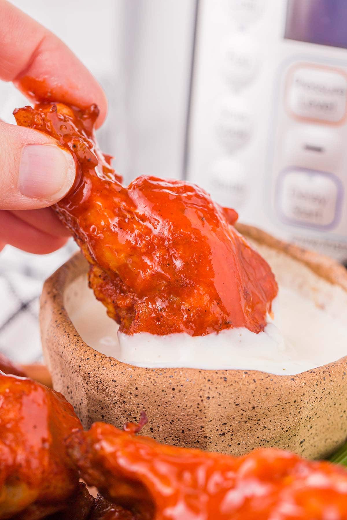 Instant Pot Buffalo Wings dipped in a ranch sauce.