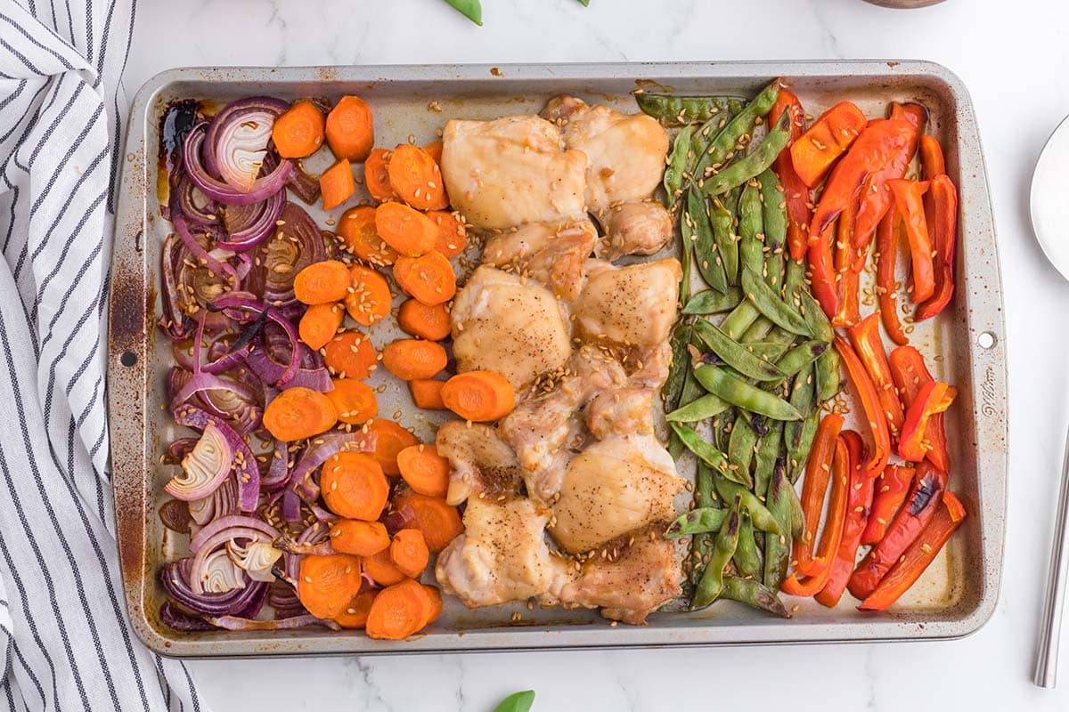 Sheet Pan Asian Chicken with various of vegetables on top of white table. 