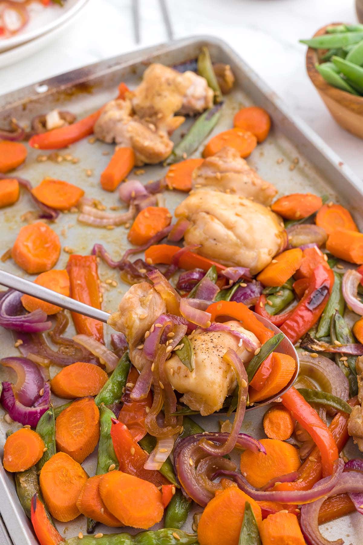 a spoonful of chicken and other veggies cooked on top of baking sheet. 