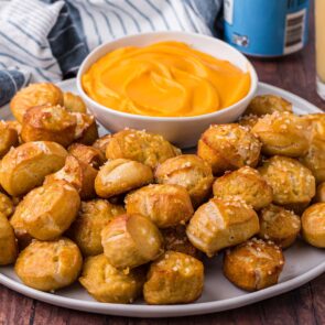 a couple of Soft Pretzel Bites in a plate with a bowl of sauce on the side.