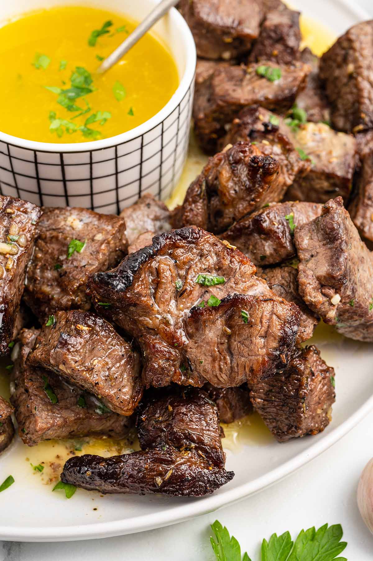 Air Fryer Steak Bites on a plate with sauce on the side. 