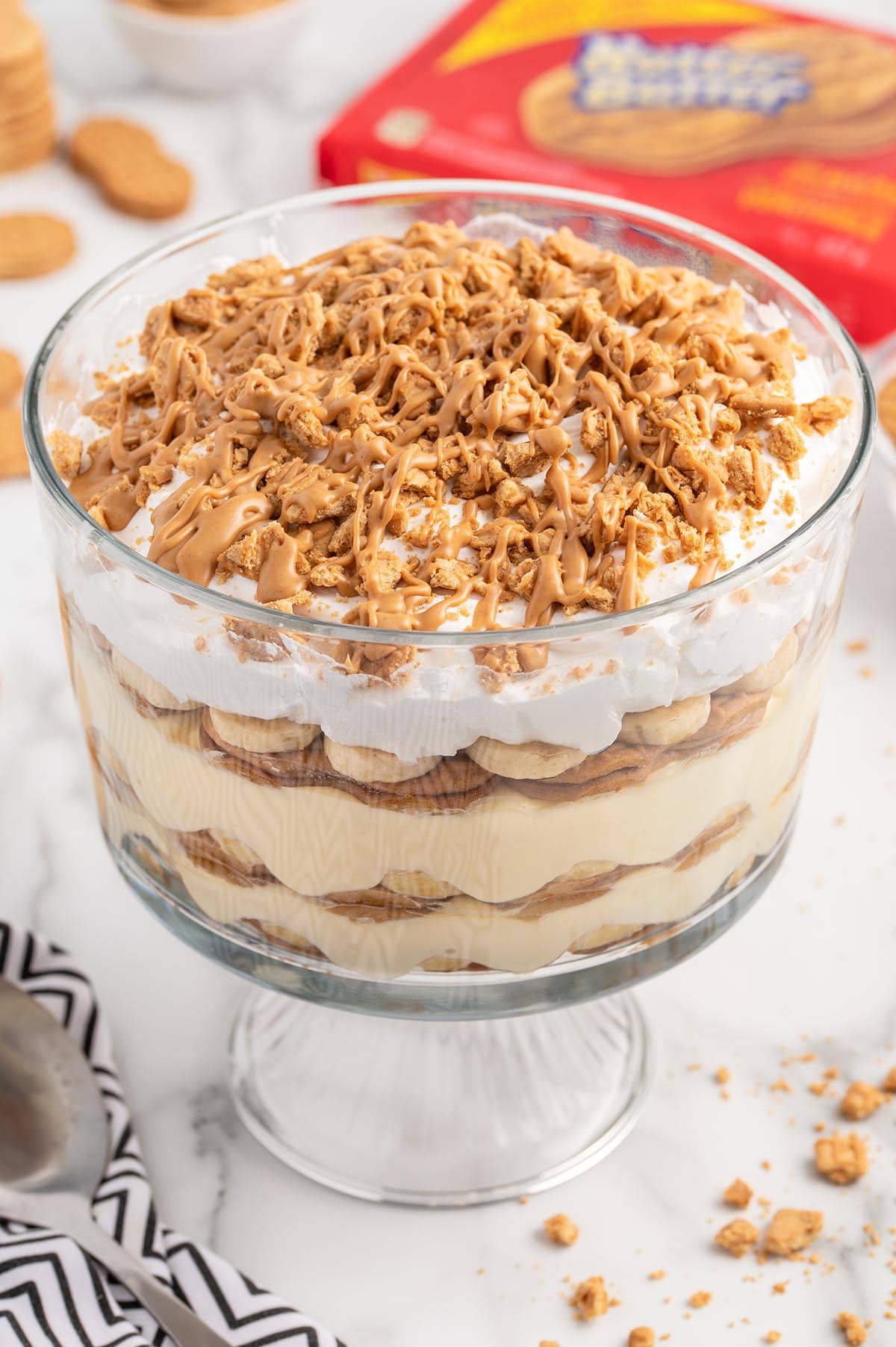 Nutter Butter Trifle on top of white table with nutter butter cookies scattered around it.