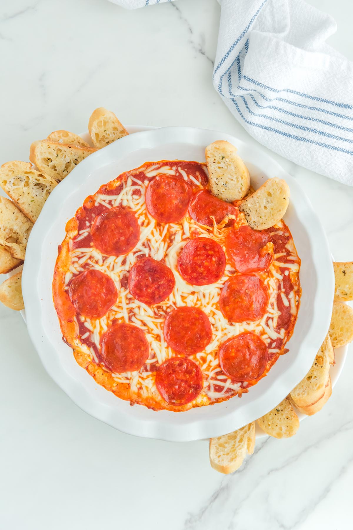 Cheese Pizza Dip in a white bowl with slices of garlic bread around it.