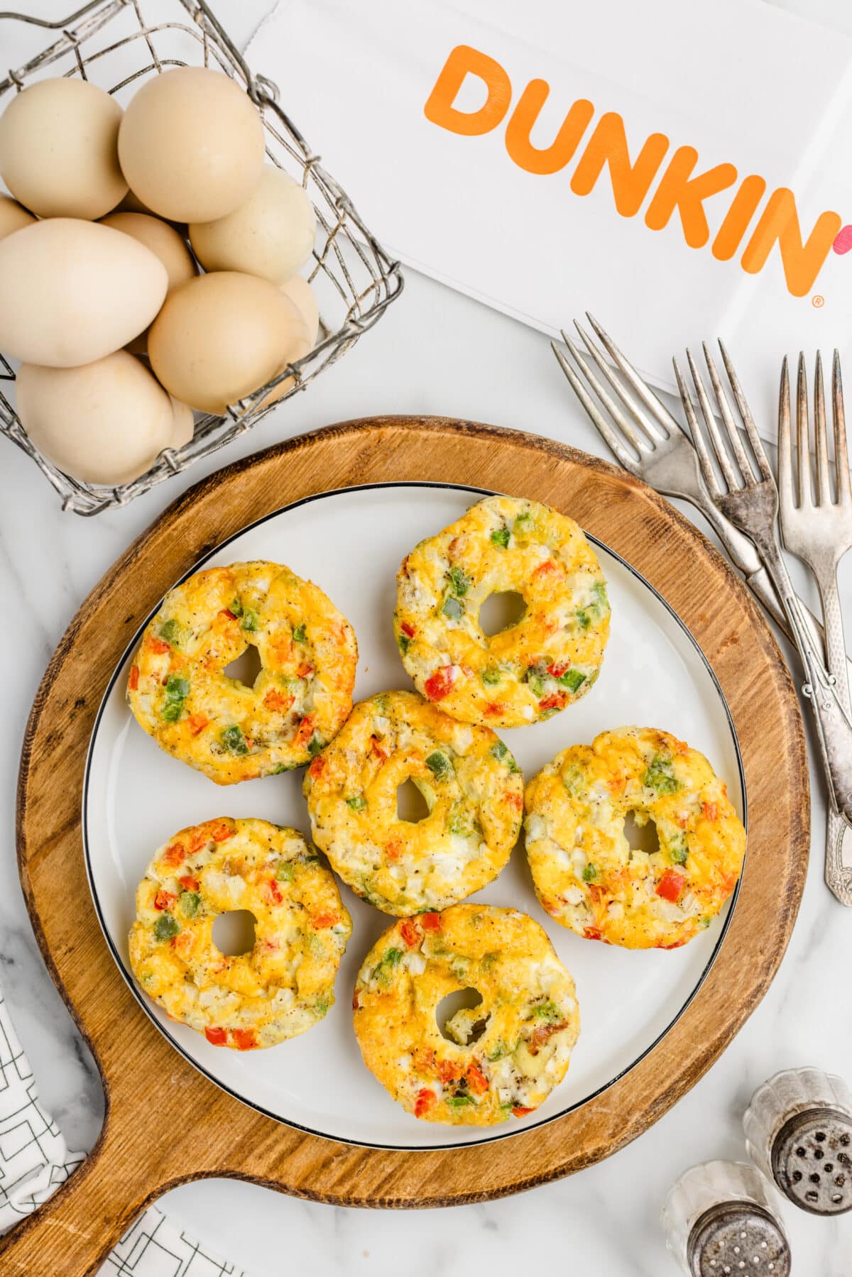 Dunkin Omelet Bites on top of a white plate with a basket of eggs on the background.