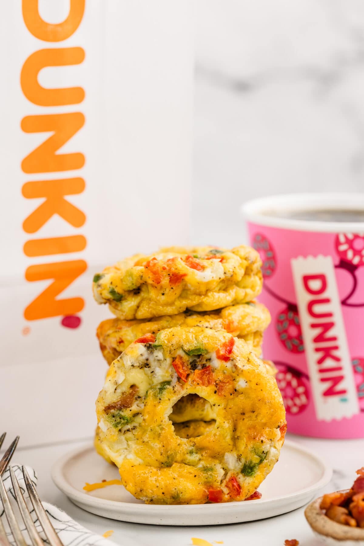 a couple of Dunkin Omelet Bites stacked with dunkin paper bag and dunkin cup on the background.