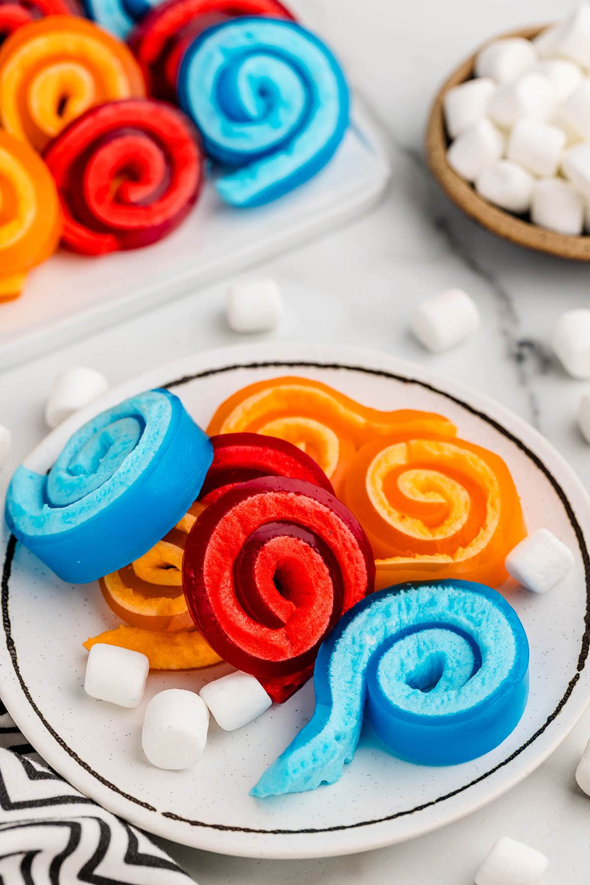 blue, red and orange jello roll ups on a plate.