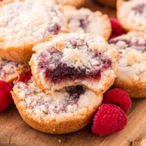 a couple of Raspberry Crumble Cookies on the table with fresh raspberries on the side.
