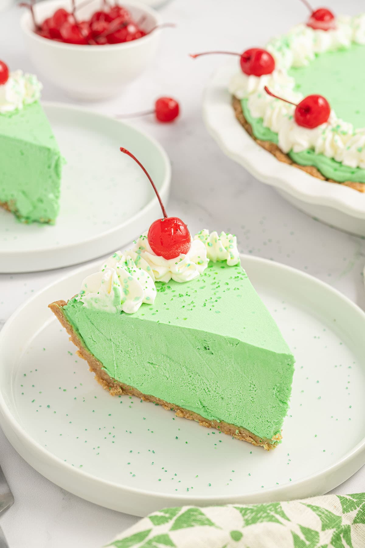 Shamrock Shake Pie on a white plate with whipped topping and cherry on top.