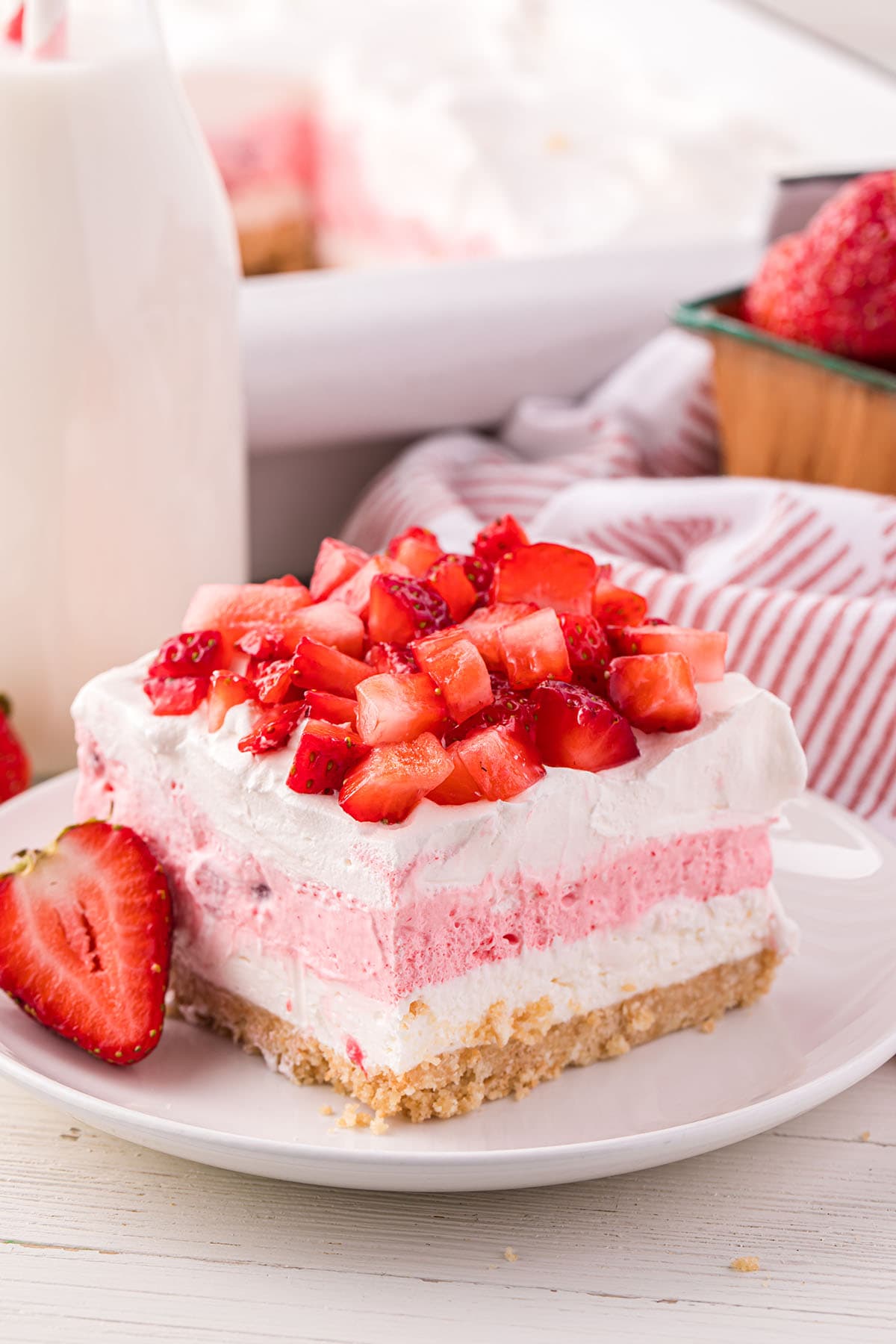 Strawberry Lasagna on a white plate with fresh strawberry on the side.