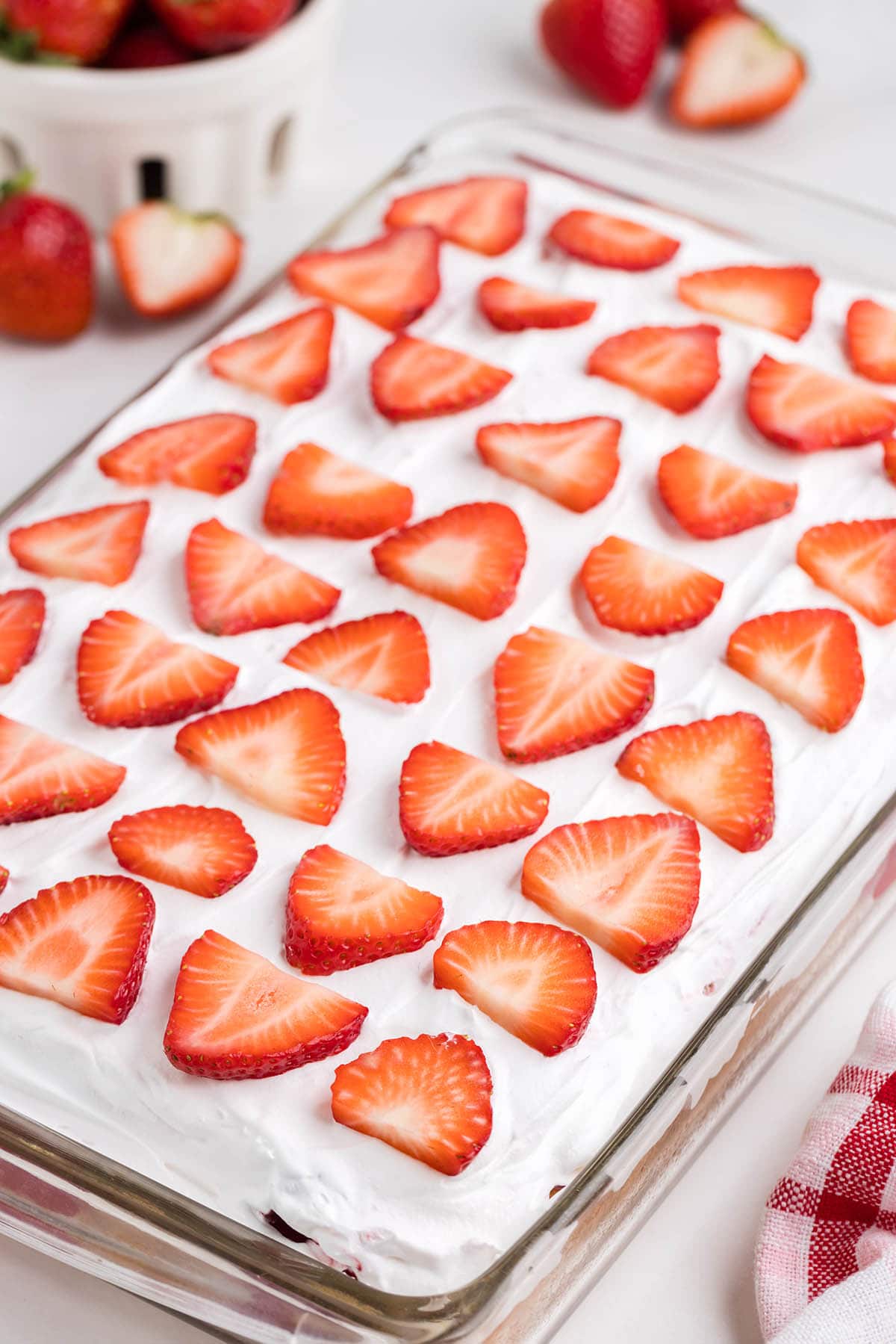 Strawberry Shortcake Poke Cake in a baking dish with strawberry slices on top.