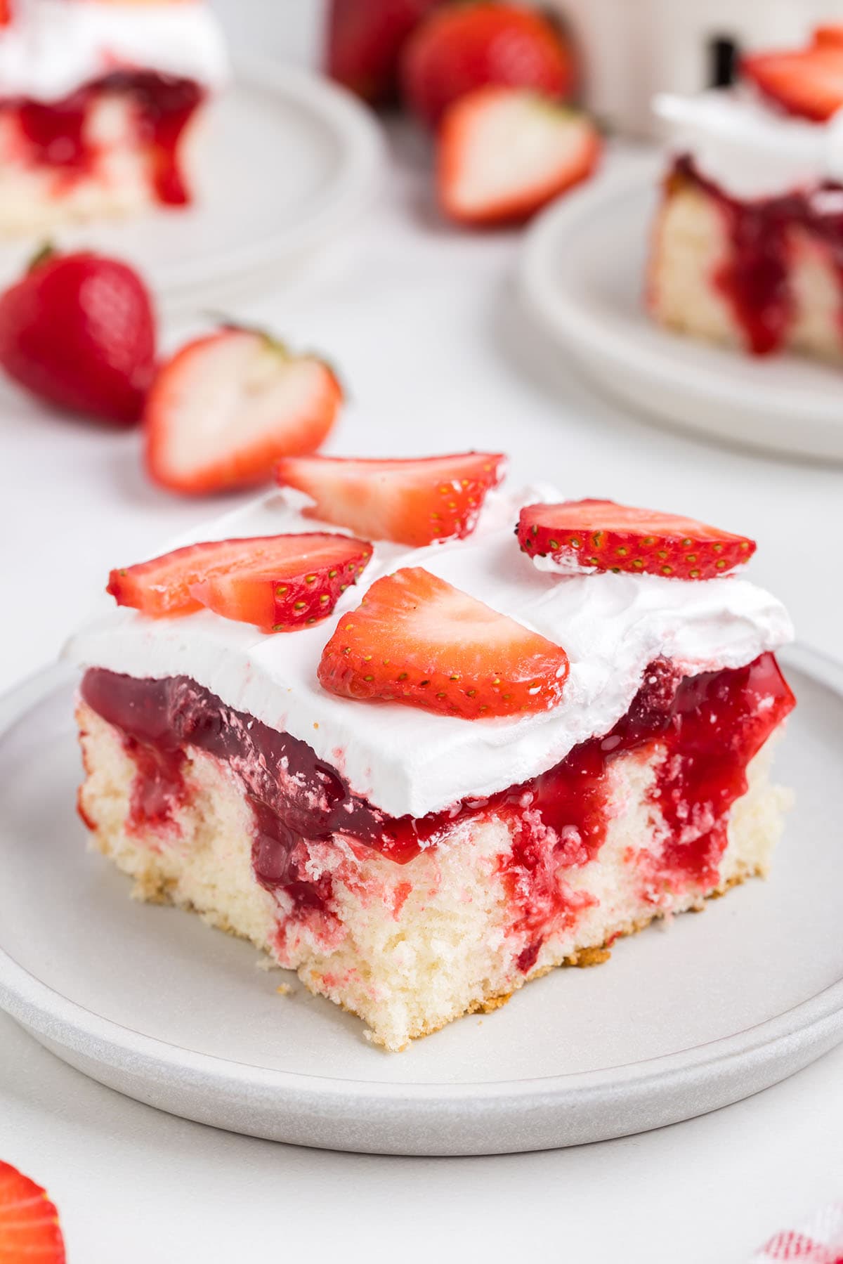 a slice of Strawberry Shortcake Poke Cake on a white plate.