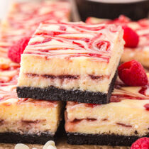 White Chocolate Raspberry Cheesecake Bars stacked on top of each other.