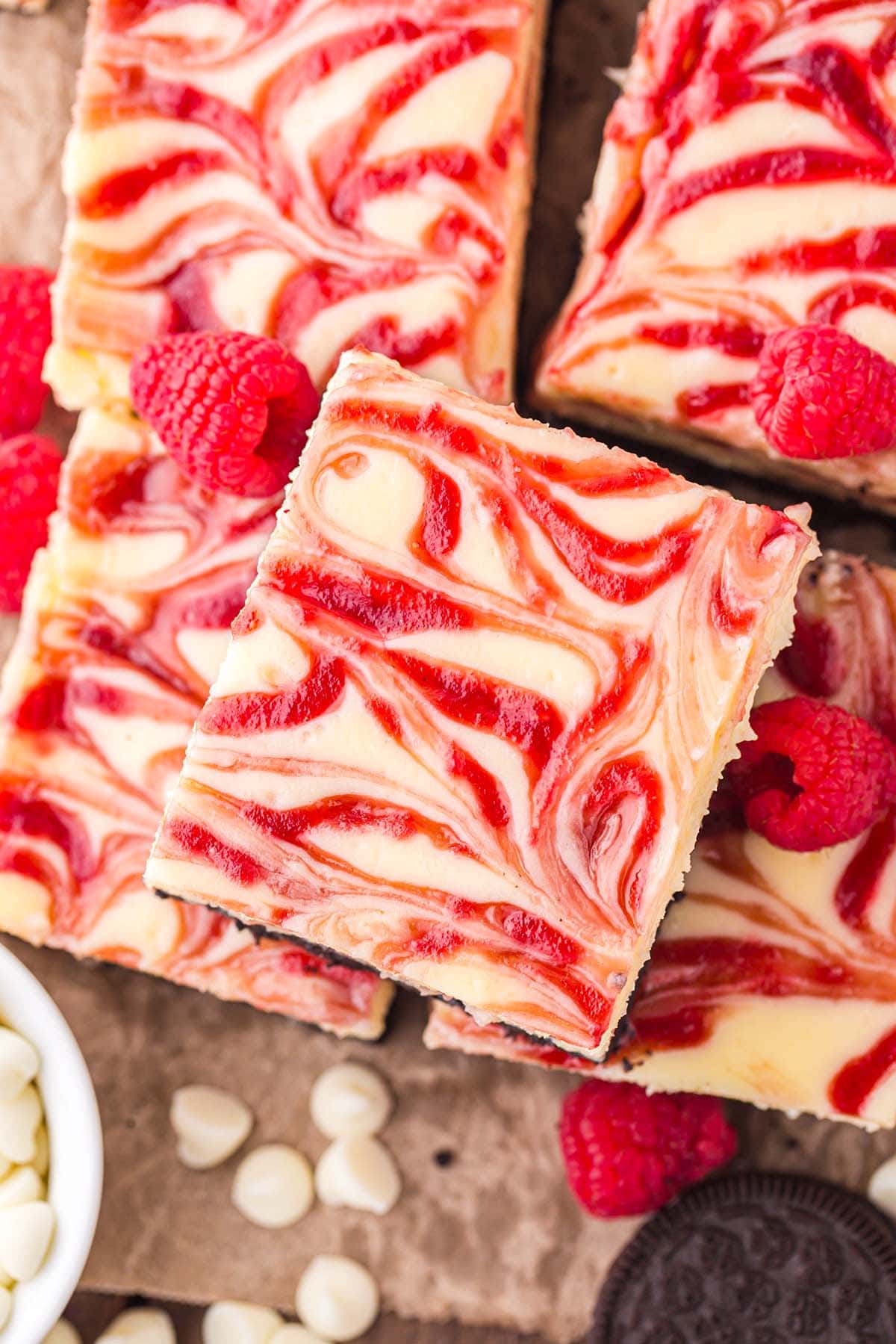 a couple of White Chocolate Raspberry Cheesecake Bars on top of parchment paper.