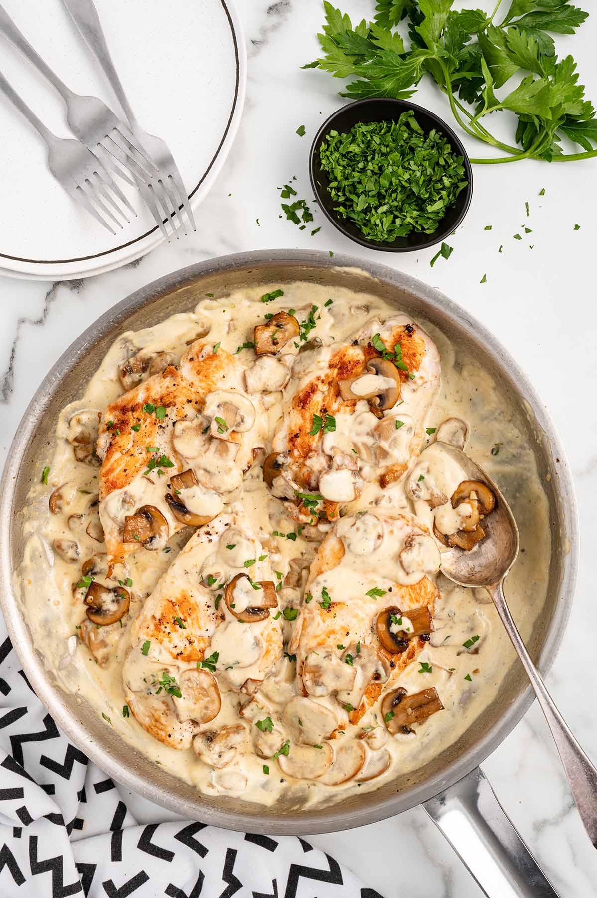 Cream of Mushroom Chicken in a skillet on top of white table.