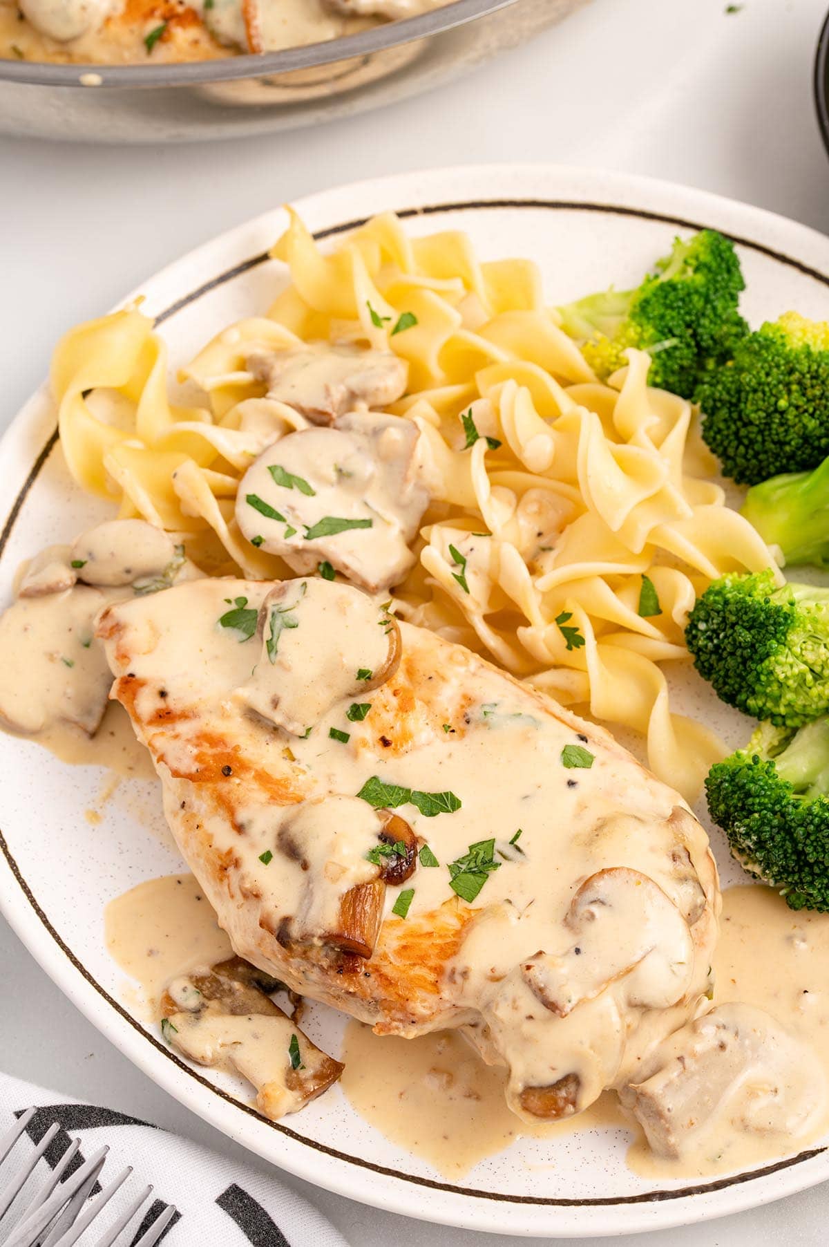 Cream of Mushroom Chicken served in a white plate with steamed broccoli.