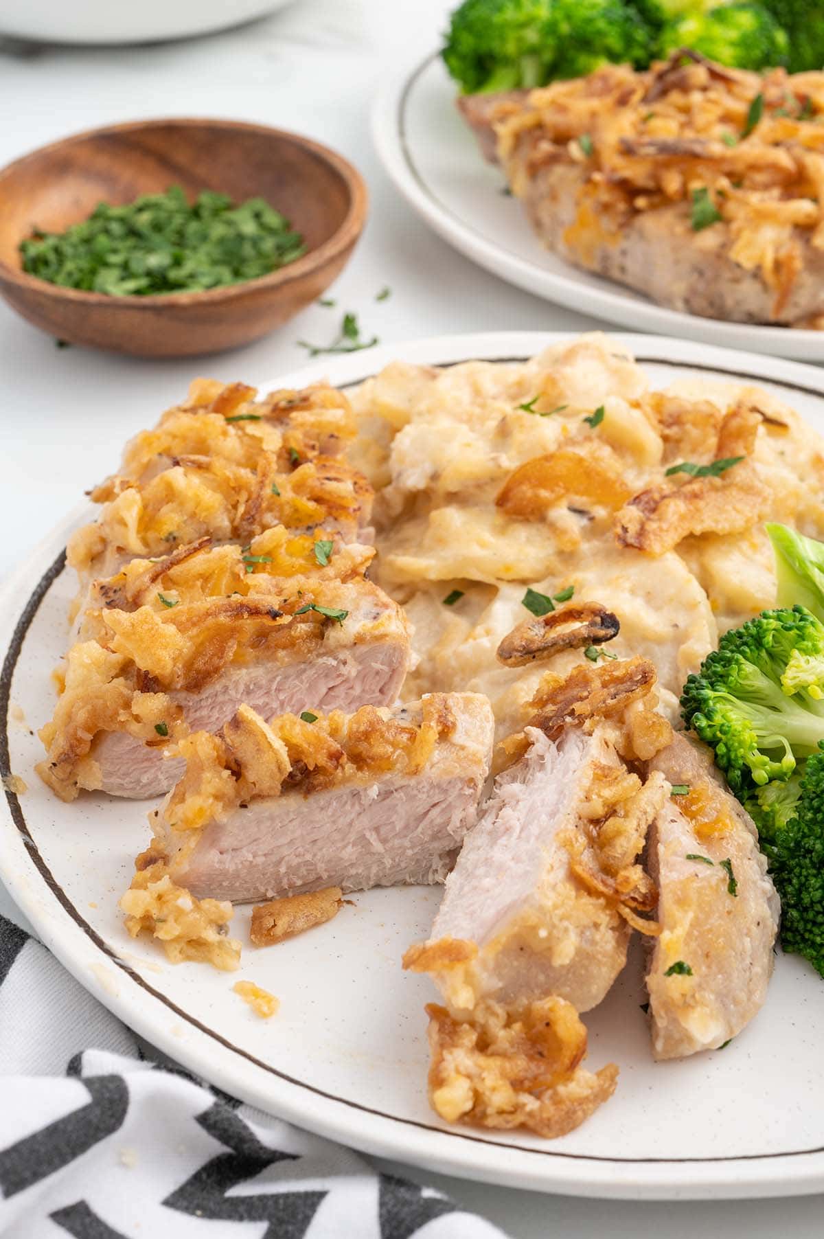 Pork Chop Casserole cut into several pieces and served with broccoli on the side.