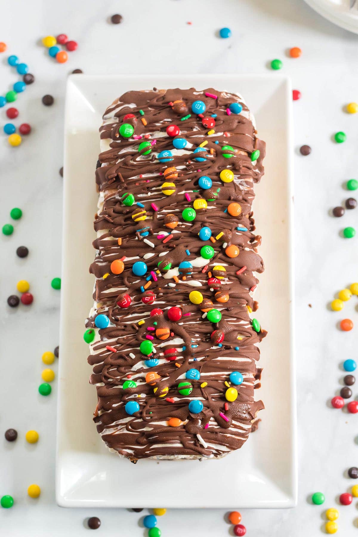 ice cream cake topped with chocolate sauce and mini m&m's.