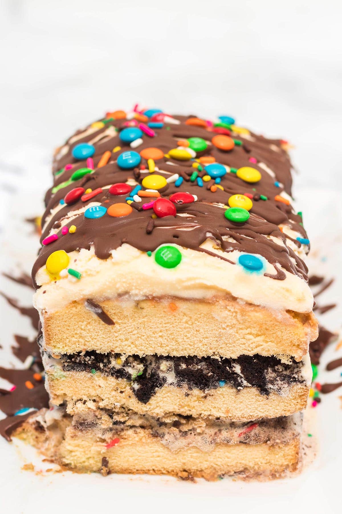 easy ice cream cake topped with chocolate sauce and mini m&m's.