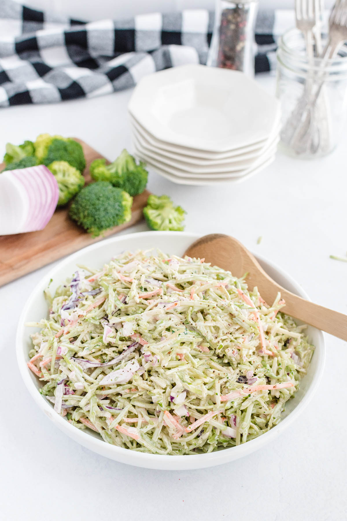 broccoli slaw in a bowl with wooden spoon on the side. 