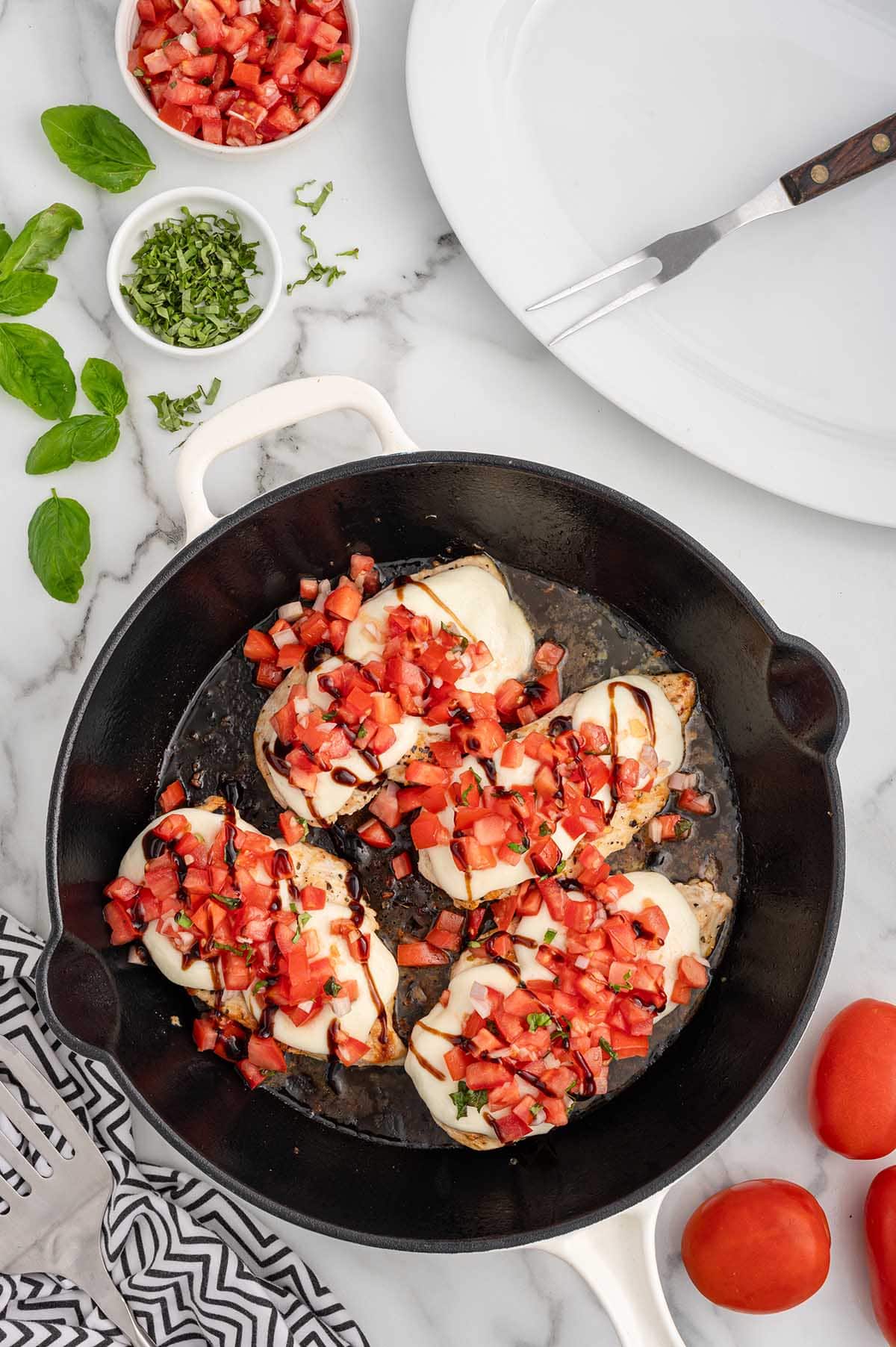 4 pieces of bruschetta chicken on a skillet.