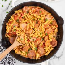 Italian Sausage Pasta in the skillet with a wooden spoon.