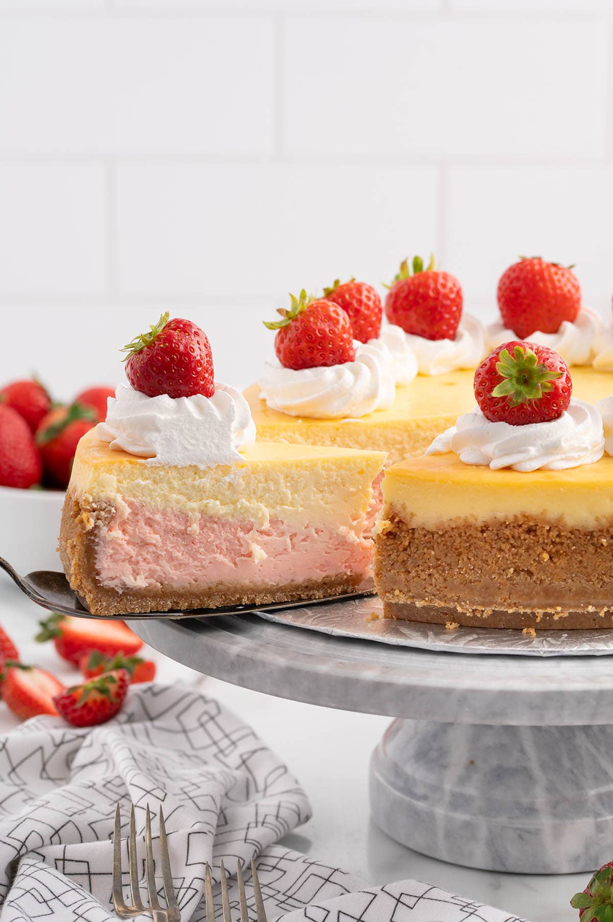 taking a slice of strawberries and cream cheesecake.