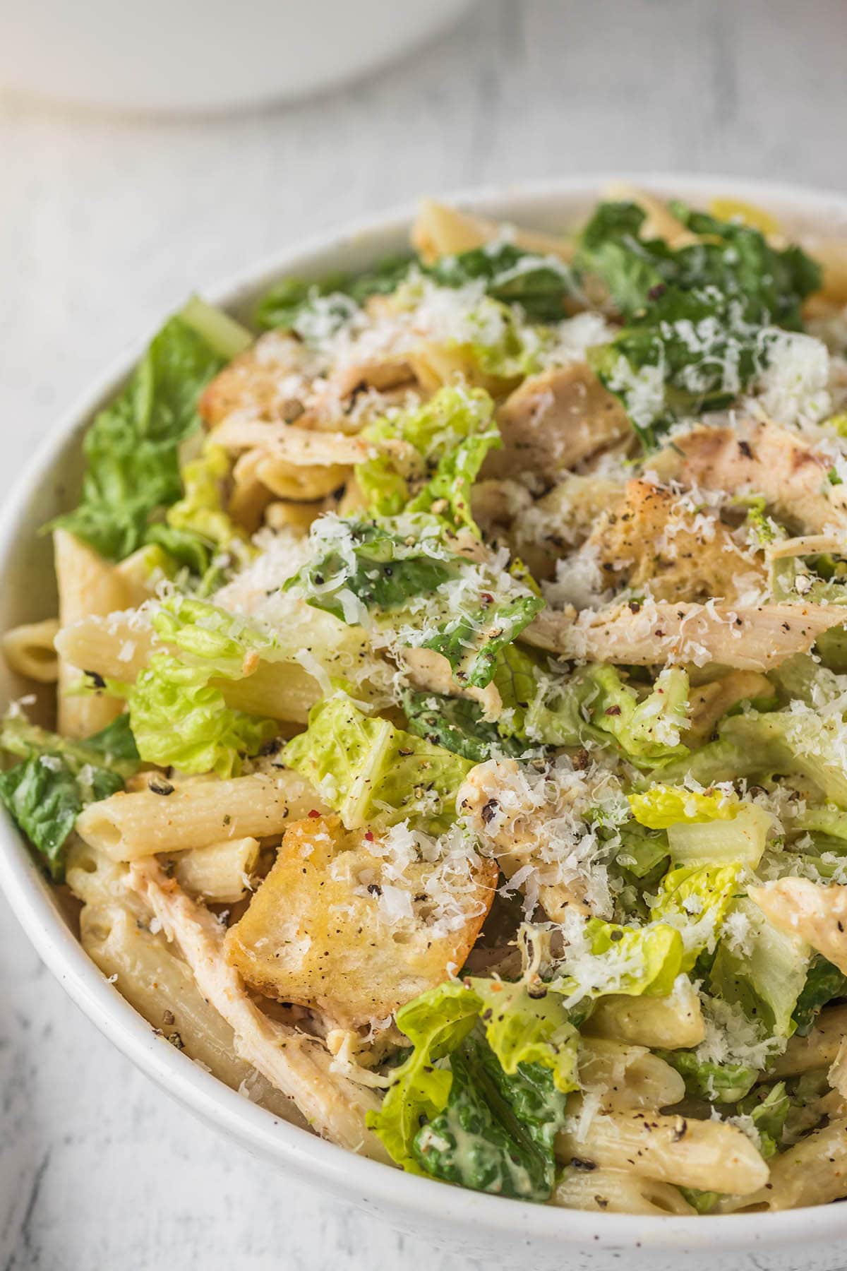 Chicken Caesar Pasta Salad garnished with parmesan cheese and black pepper.
