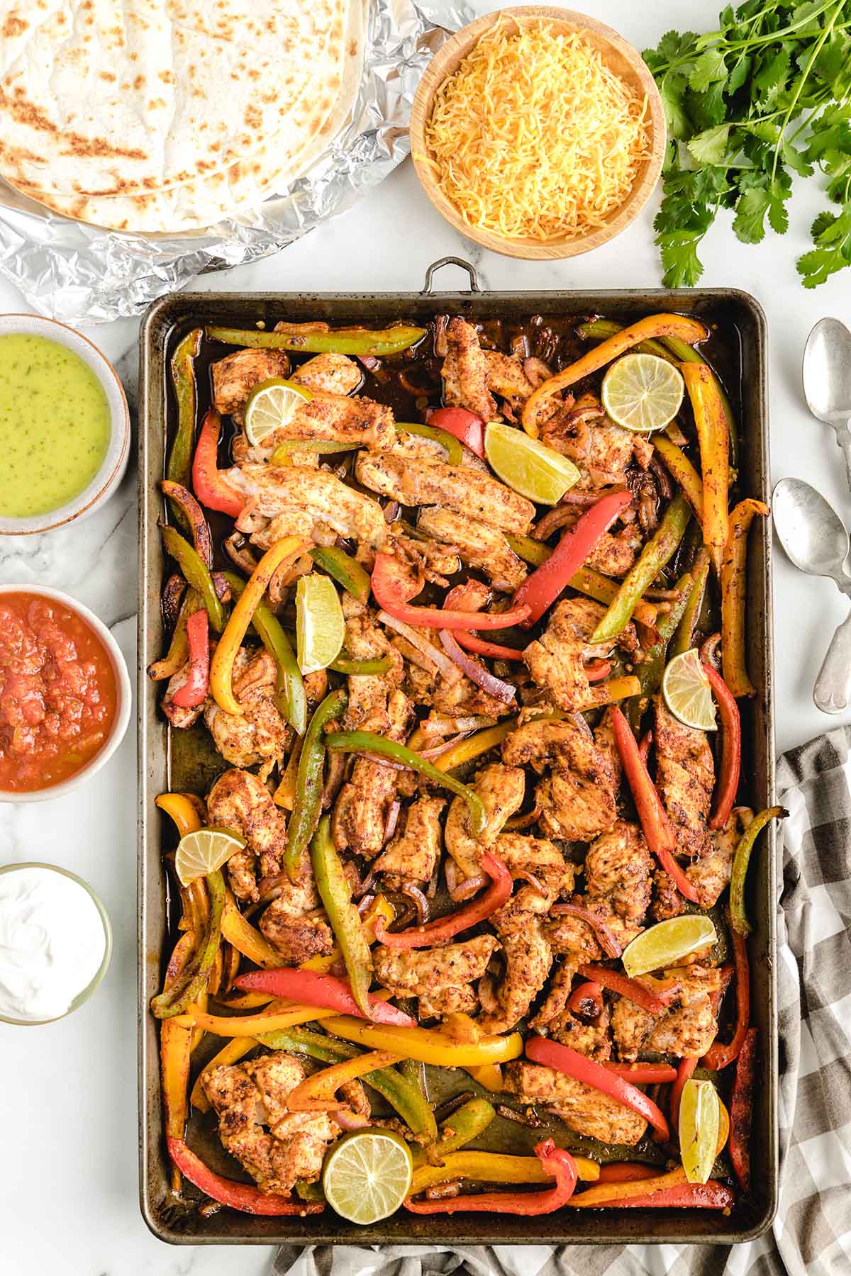 fajitas in a sheet pan with a bowl of shredded cheese on the side.