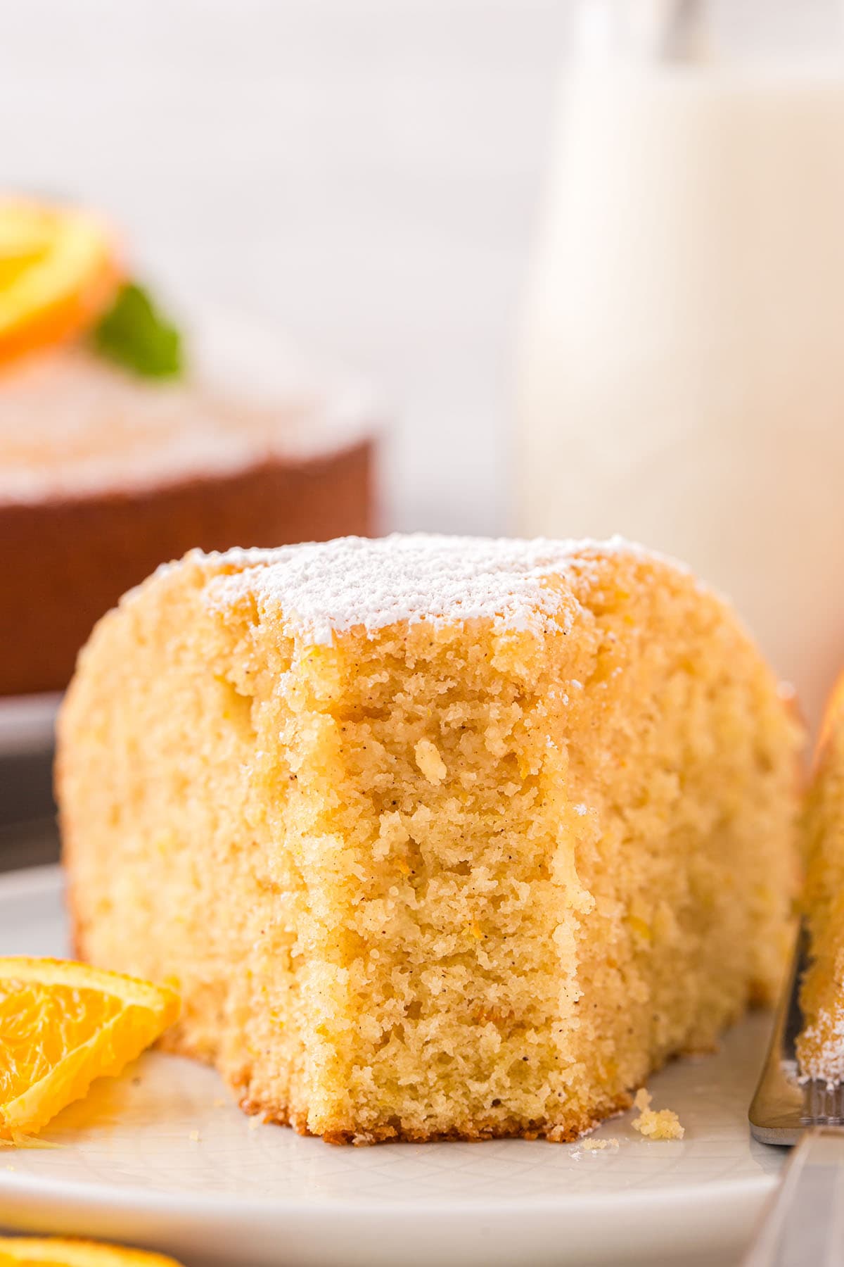 a slice of Orange Cake on a plate with orange slices on the side.