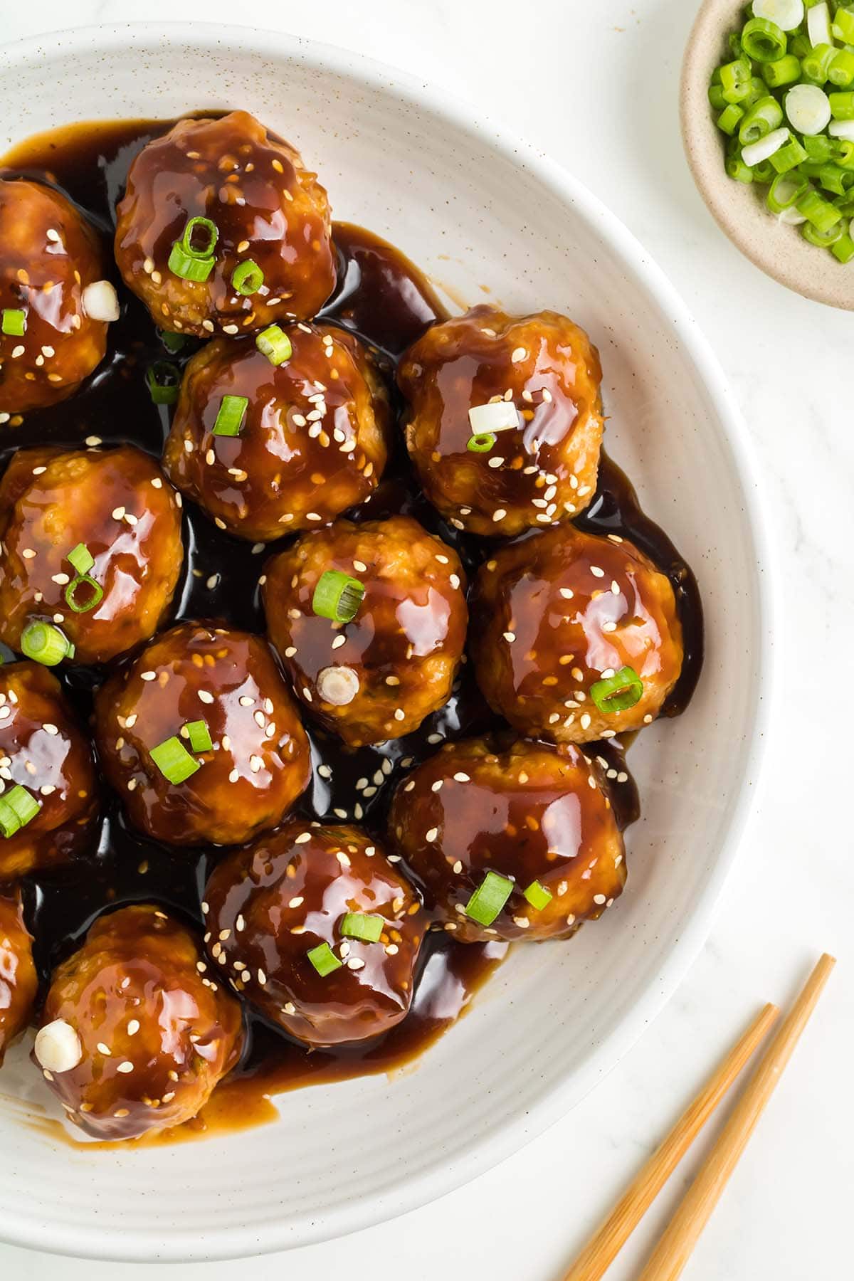 Teriyaki Meatballs garnished with sesame seeds and green onions in a large bowl.