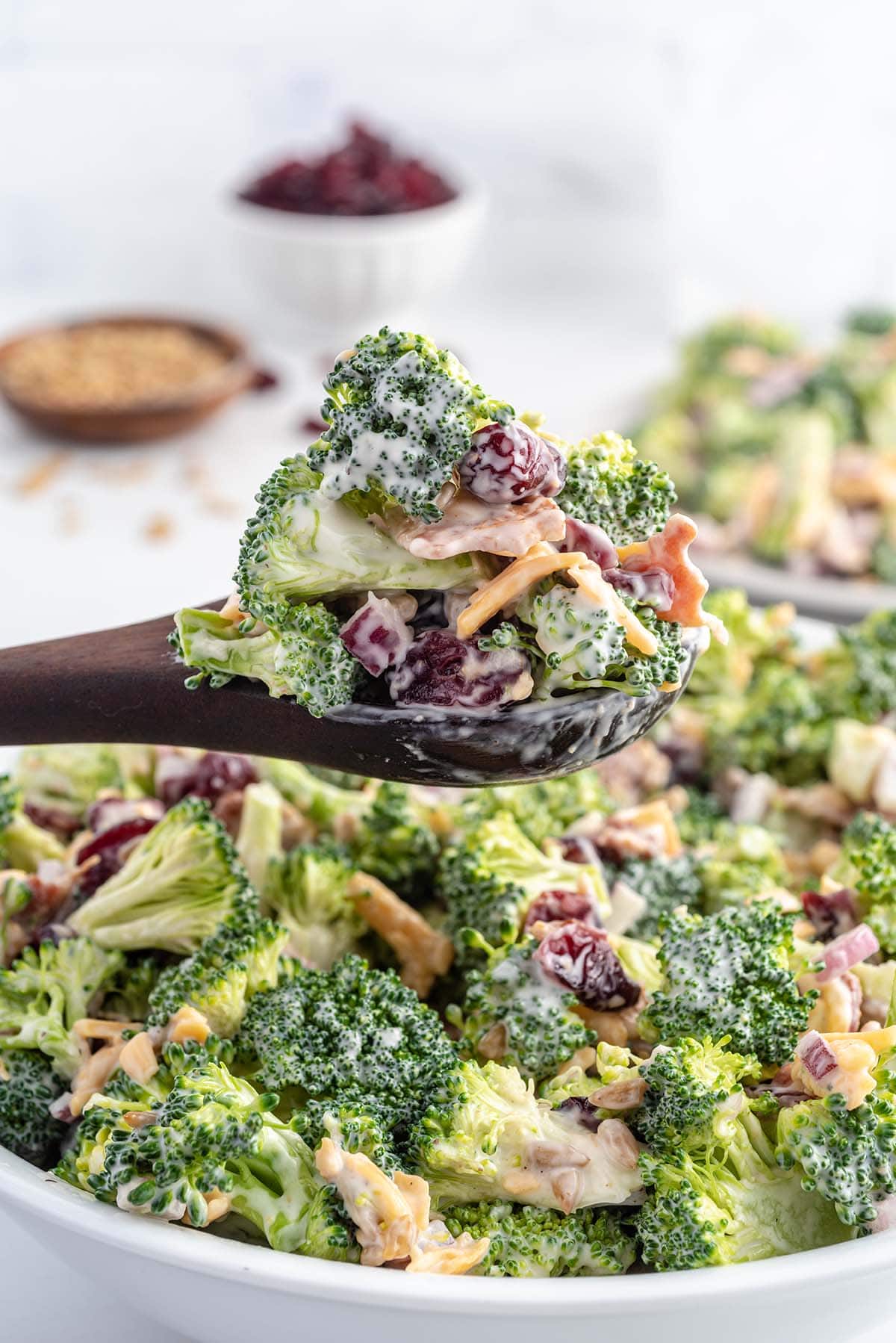 taking a spoonful of broccoli salad using wooden spoon.
