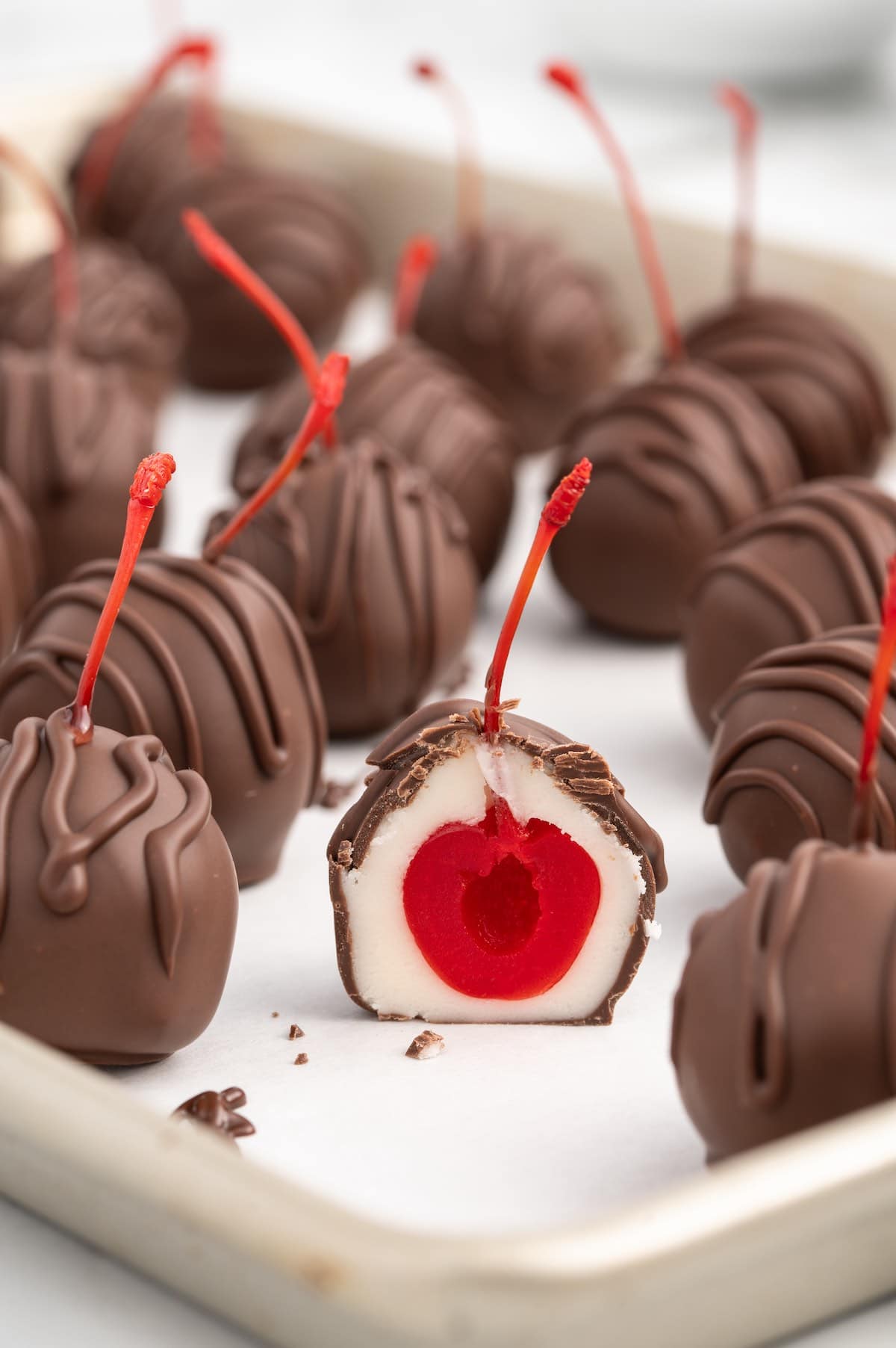 Chocolate Covered Cherries split in half and placed together with the other cherries in baking sheet.