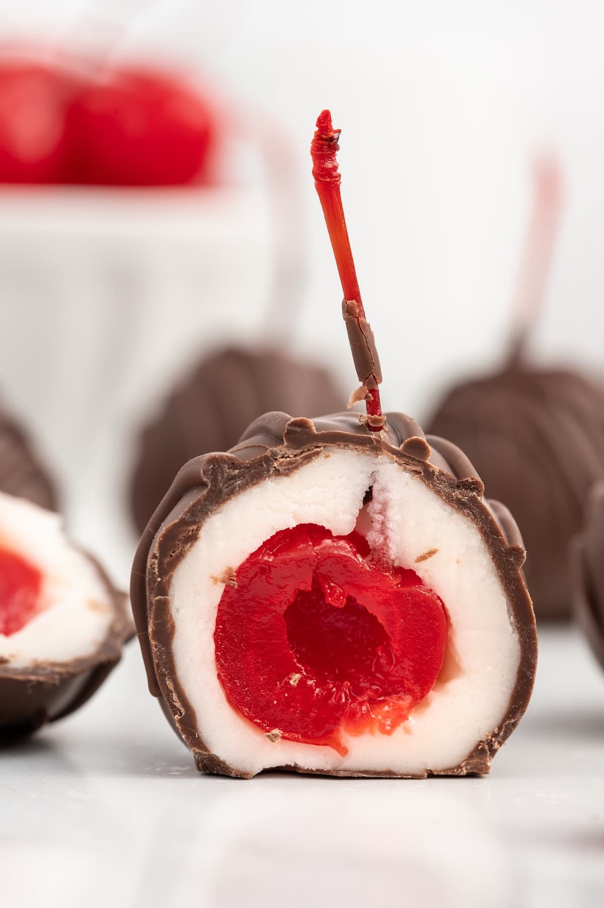 Chocolate Covered Cherries cut in half and placed on top of white table. 